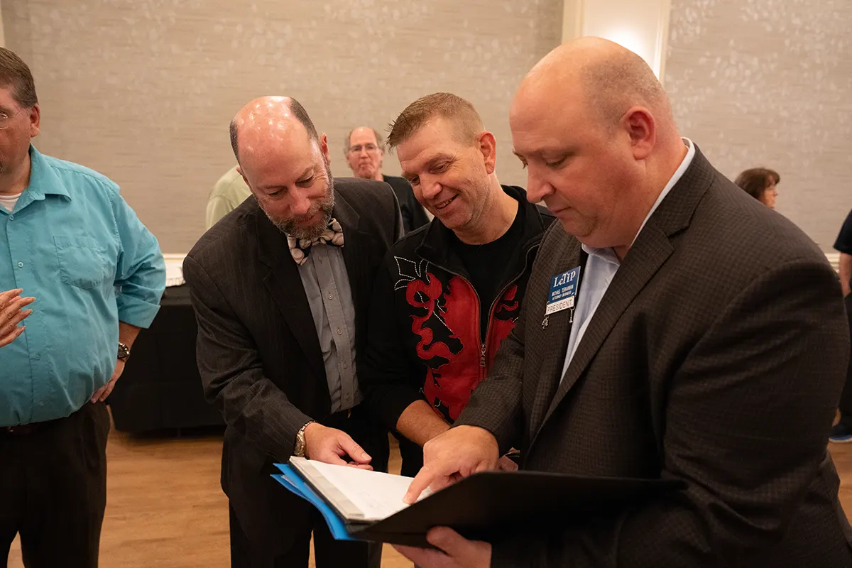 Three guys looking at padfolio at LeTip